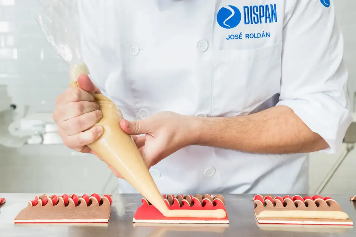 Maestro pastelero preparando masa en un obrador profesional durante una sesión culinaria