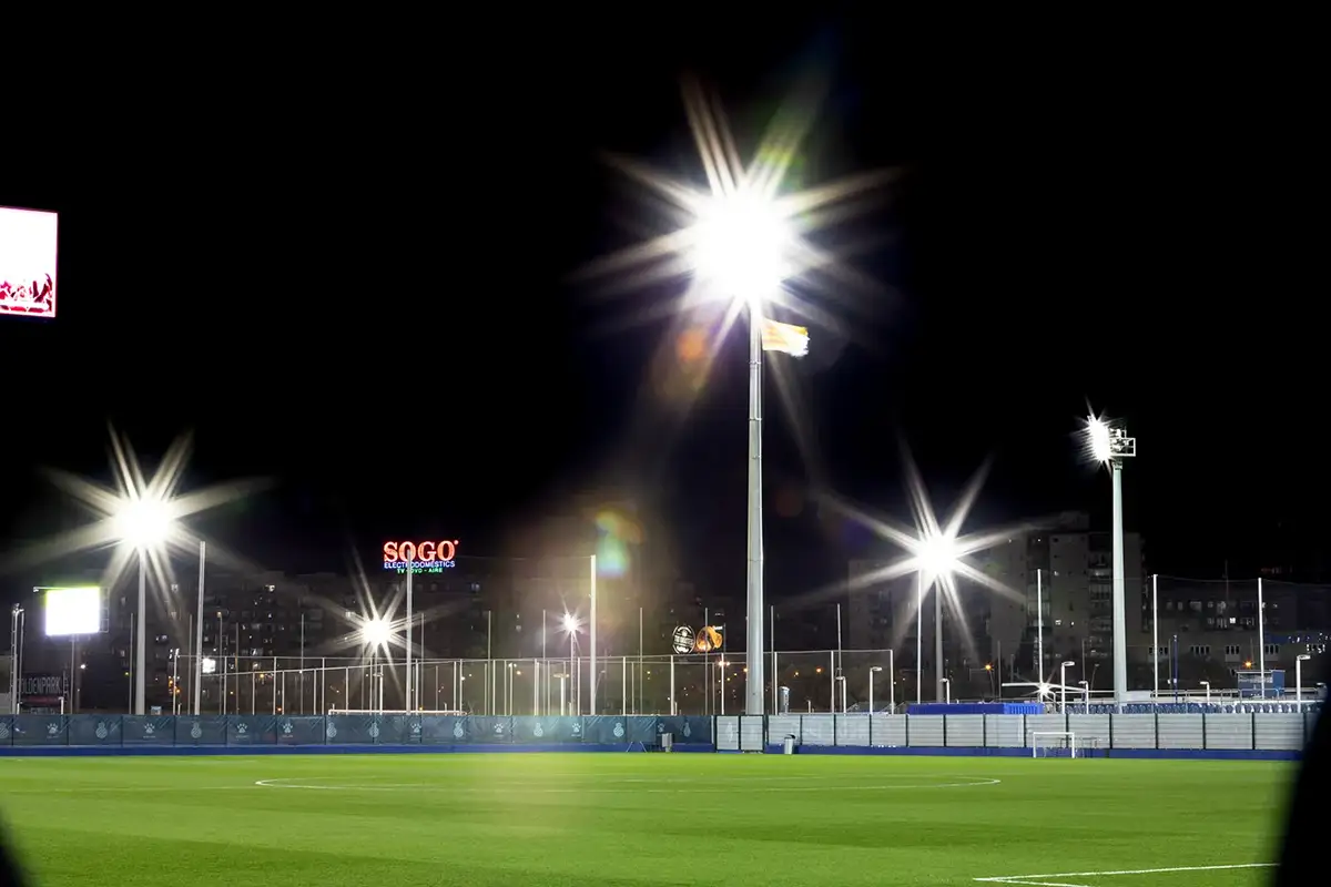 Campo de fútbol profesional iluminado de noche con focos de gran altura y cielo negro