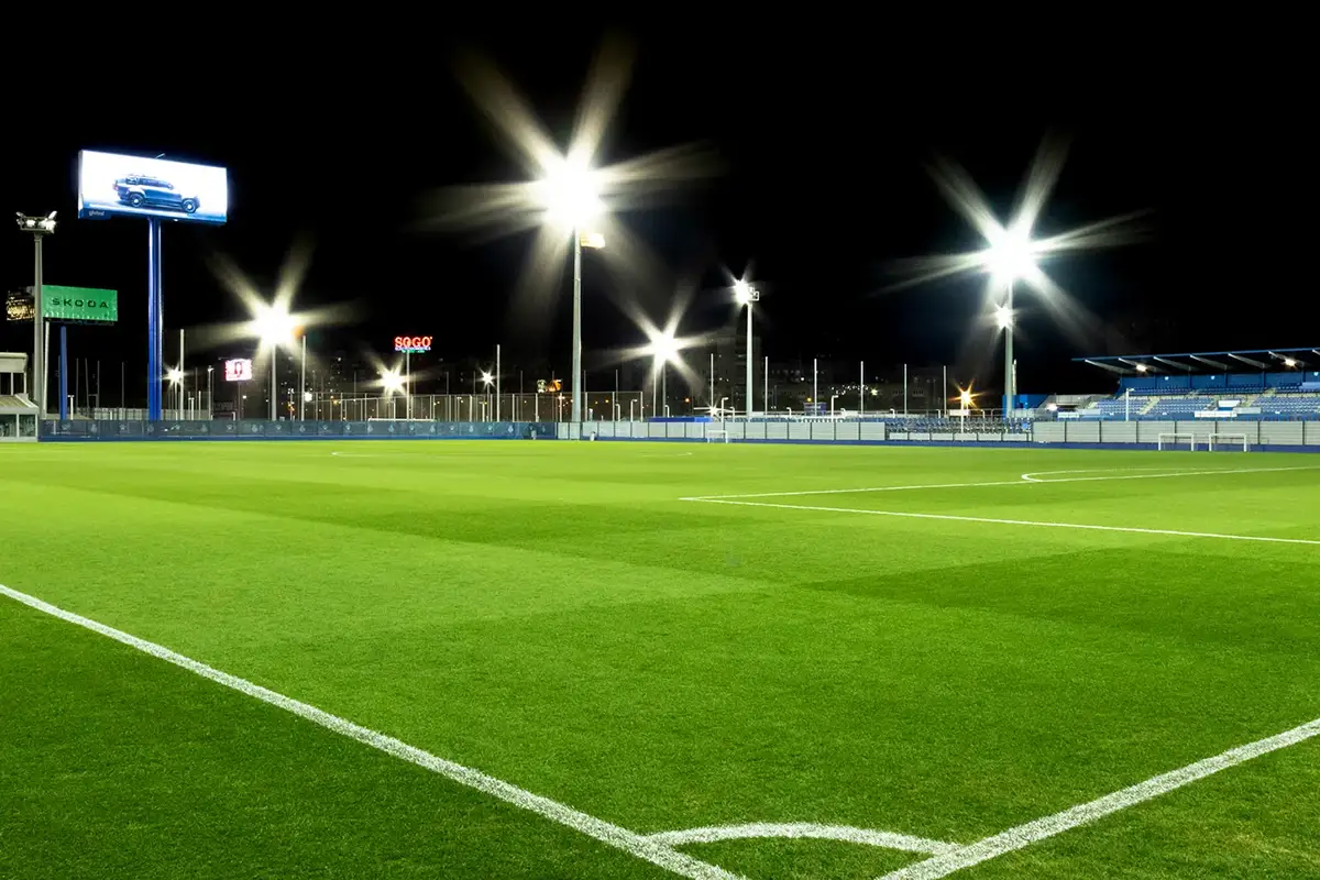 Fotografía desde la esquina del campo de futbol con césped perfectamente iluminado por proyectores