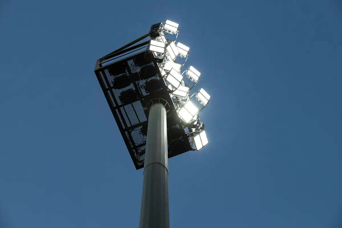 Fotografía de una torre de iluminación con módulos LED muy potentes encendidos sobre cielo azul