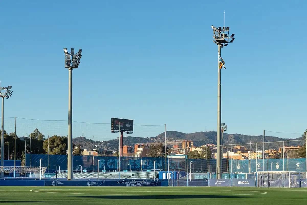 Fotografía de mástiless de iluminación vistos a plena luz del día con la ciudad y montañas al fondo