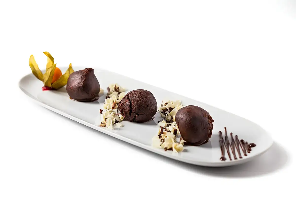 Fotografía de carta de postre de chocolate emplatado con virutas y decoración en plato alargado