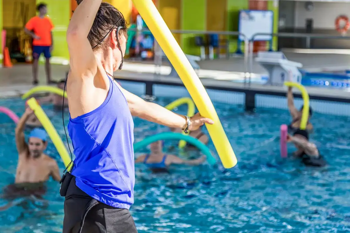 Miniatura de monitora guiando clase de aquagym en piscina cubierta