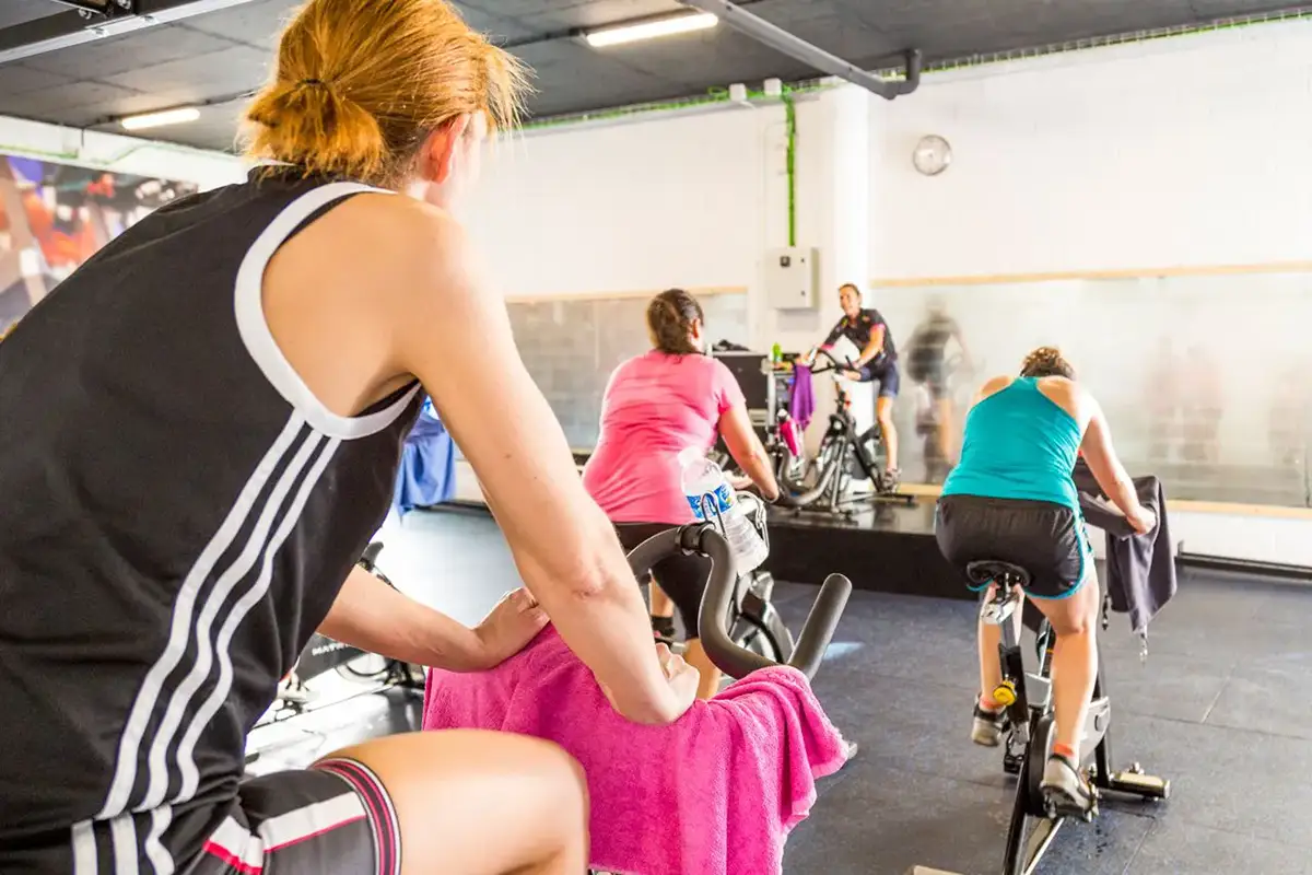 Fotografía de clase de ciclo indoor con instructora al fondo