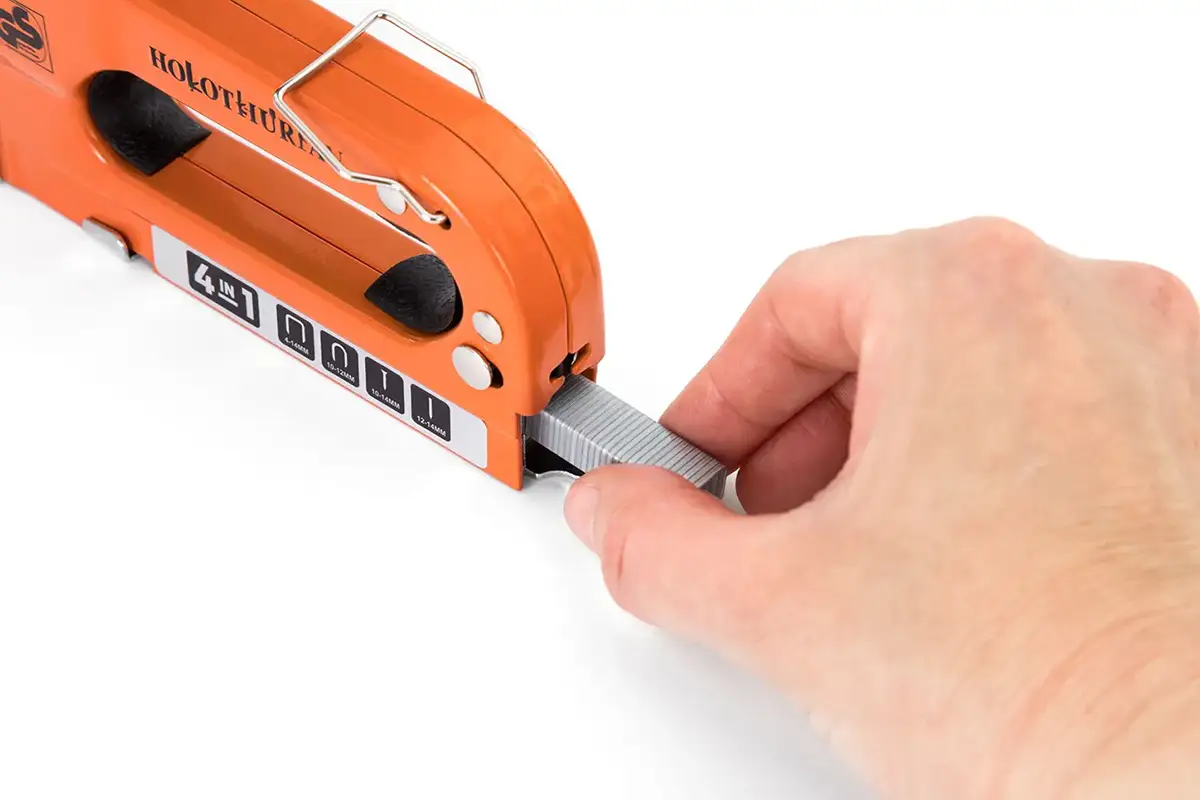 Fotografía de una mano introduciendo un cargador de grapas en el compartimento de la grapadora de mano para Amazon