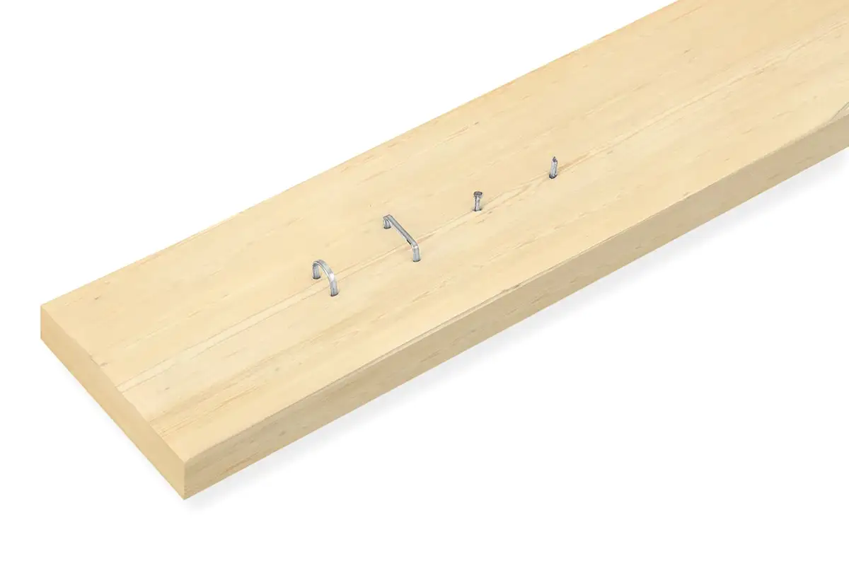 Fotografía de un listón de madera donde se aprecian distintos tipos de grapas y clavos parcialmente insertados para comparar su uso en Amazon